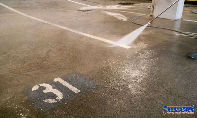 Technician is performing pressure washing service in an underground parking