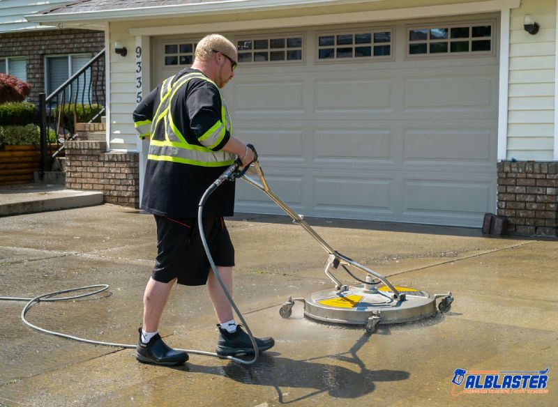 Technician is performing residential pressure washing on a driveway