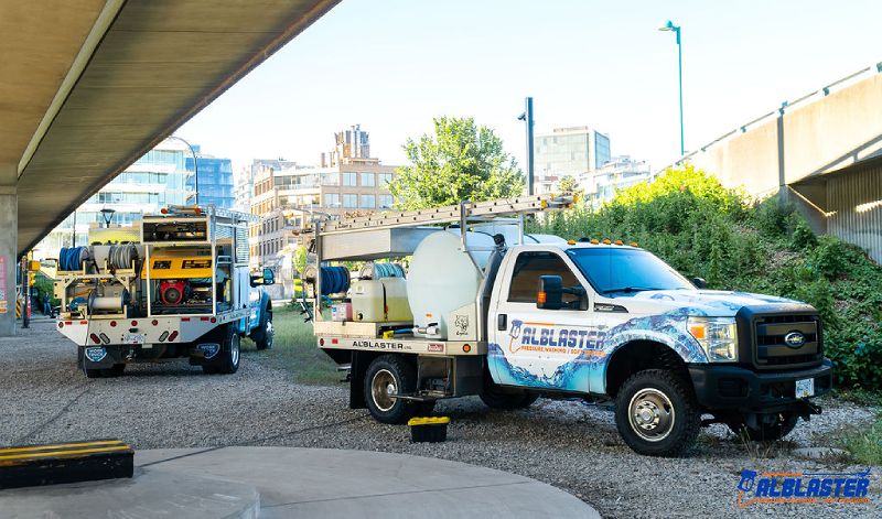 Alblaster pressure washing trucks are parked under Cambie Bridge before starting the job.