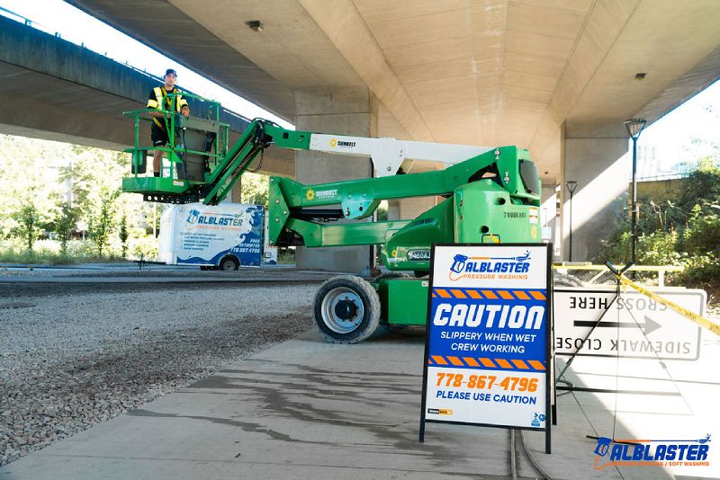 A pressure washing contractor is adjusting the ladder before start washing the bottom of the bridge.