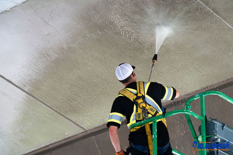 A contractor on a ladder is performing pressure washing on Cambie Bridge in Vancouver