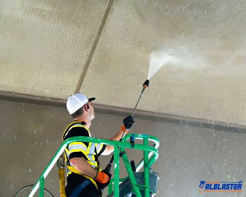 A contractor on a ladder is performing pressure washing on Cambie Bridge in Vancouver