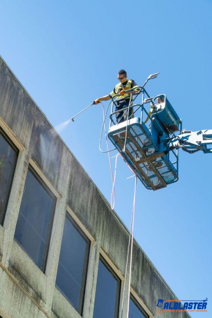 Soft washing from a ladder on a commercial building