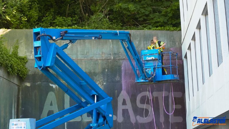 Pressure washing from a ladder on a parking wall