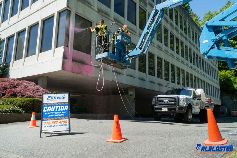 Soft washing from a ladder on a commercial building's facade