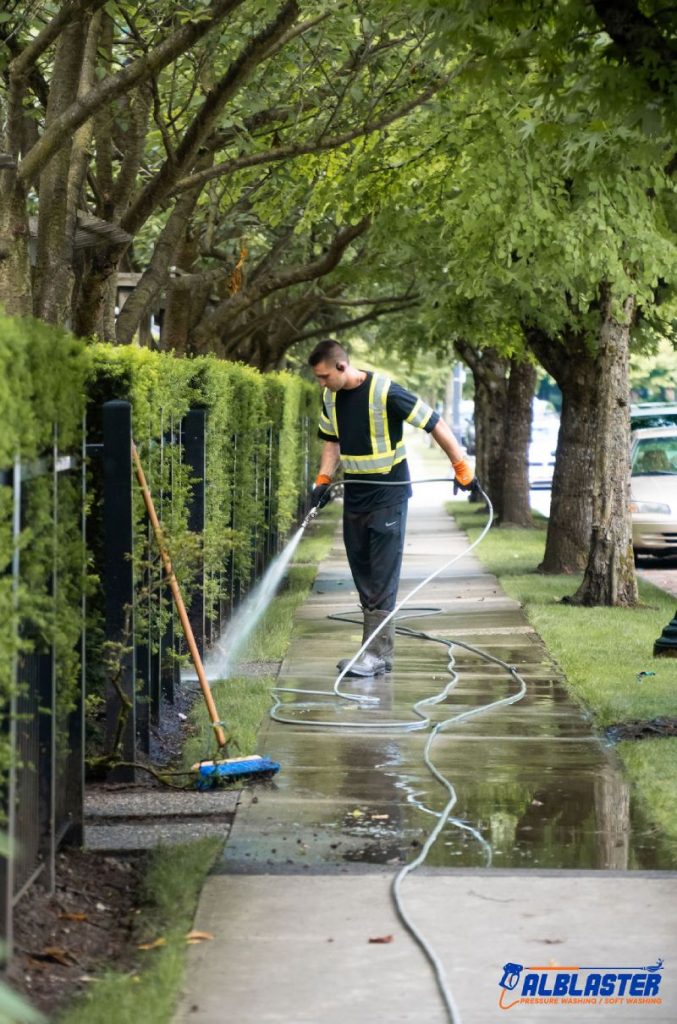 Crew member pressure washing a sidewalk